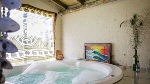 Un bain à remous avec un plafond en bois, une tapisserie et un tableau au mur.
