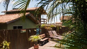 Une terrasse en bois avec une piscine, une clôture en bois et un bâtiment doté d’un toit en tuiles.