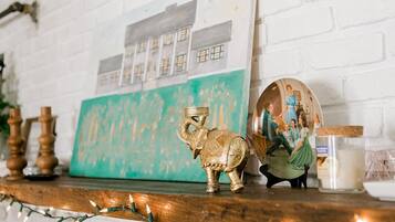 A white brick fireplace with a framed picture above it, a small elephant figurine, and a candle holder.
