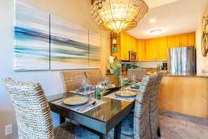 Zona pranzo con tavolo in vetro, sedie in vimini e lampadario moderno.