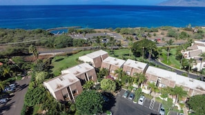 A residential area with a view of the ocean, featuring modern buildings, a parking lot, and lush greenery.