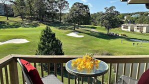 Un balcon avec une table et des chaises donnant sur un terrain de golf.