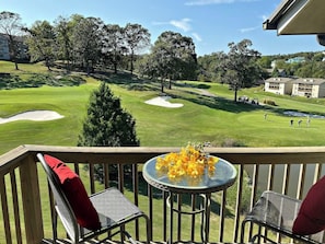 A balcony with a table and chairs overlooking a golf course. - The Loft at Pointe Royale Resort (Branson)