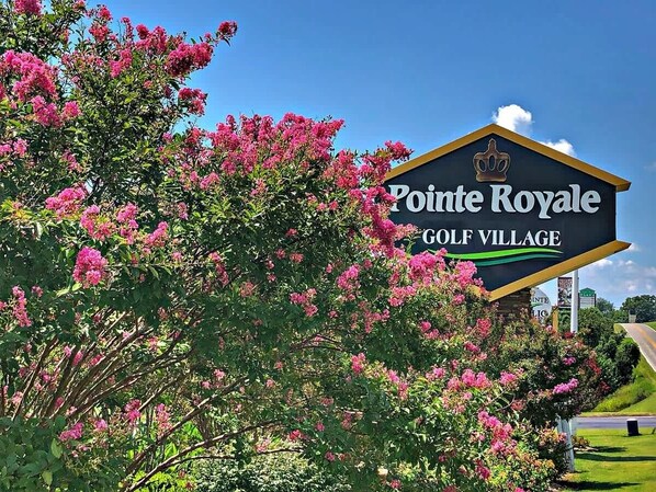 A sign for Pointe Royale Golf Village with a crown emblem.