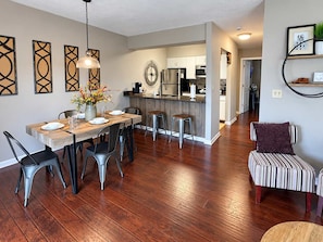 A modern kitchen with a central island, dining area with chairs and a table, and a striped bench.