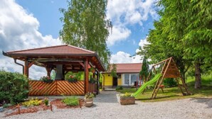 Katettu ulkoalue, jossa on puinen rakenne, keltainen rakennus ja vihreä liukumäki.