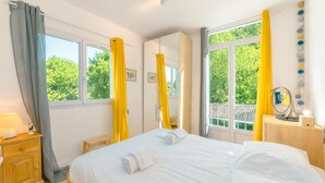 Una habitación de hotel con cama, mesita de noche, espejo y ventana con cortinas.