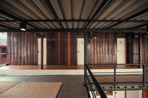 A room with wooden panel walls, a metal ceiling, and a wooden floor. There are two doors labeled 'D' and 'E'. - Sylvis Hostel Chiangmai (Chiang Mai)