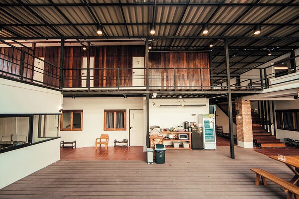 A spacious indoor area with a wooden floor, a kitchen area, and a staircase leading to an upper level.