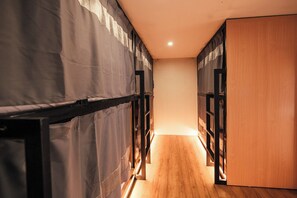 A corridor with bunk beds, wooden flooring, and a wooden door.