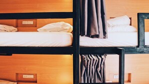 A bunk bed room with wooden headboards and a single bed with a white mattress and brown curtains. - Sylvis Hostel Chiangmai (Chiang Mai)