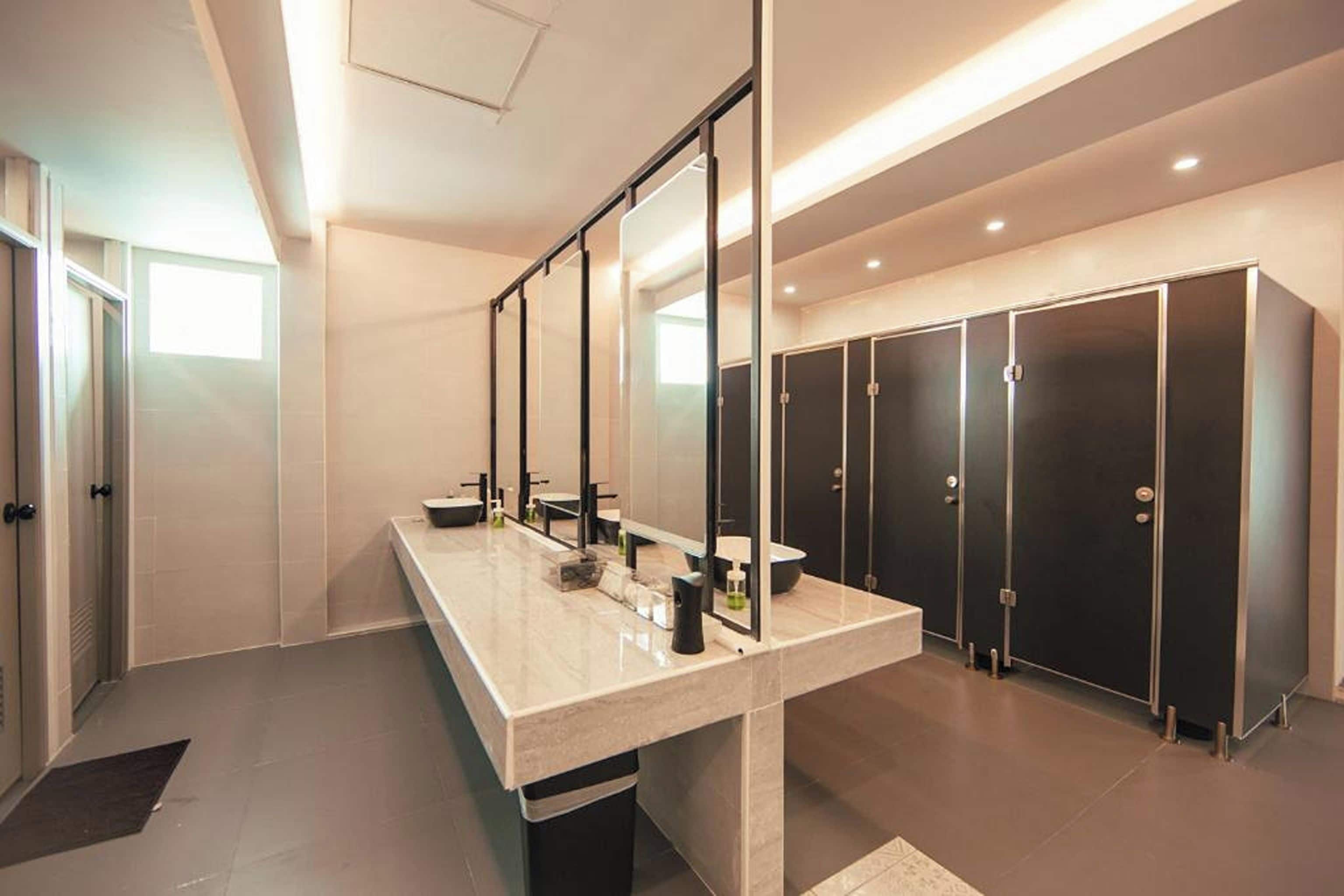 A modern bathroom with a long vanity, multiple sinks, and a row of lockers.