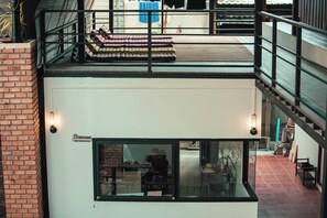 A two-story building with a balcony, a dining area, and a visible kitchen. - Sylvis Hostel Chiangmai (Chiang Mai)