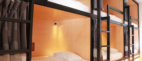 Dormitorio con literas de madera y ropa de cama blanca.