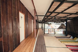 A corridor with wooden walls and a wooden floor, leading to a covered area with a view of the outside. - Sylvis Hostel Chiangmai (Chiang Mai)