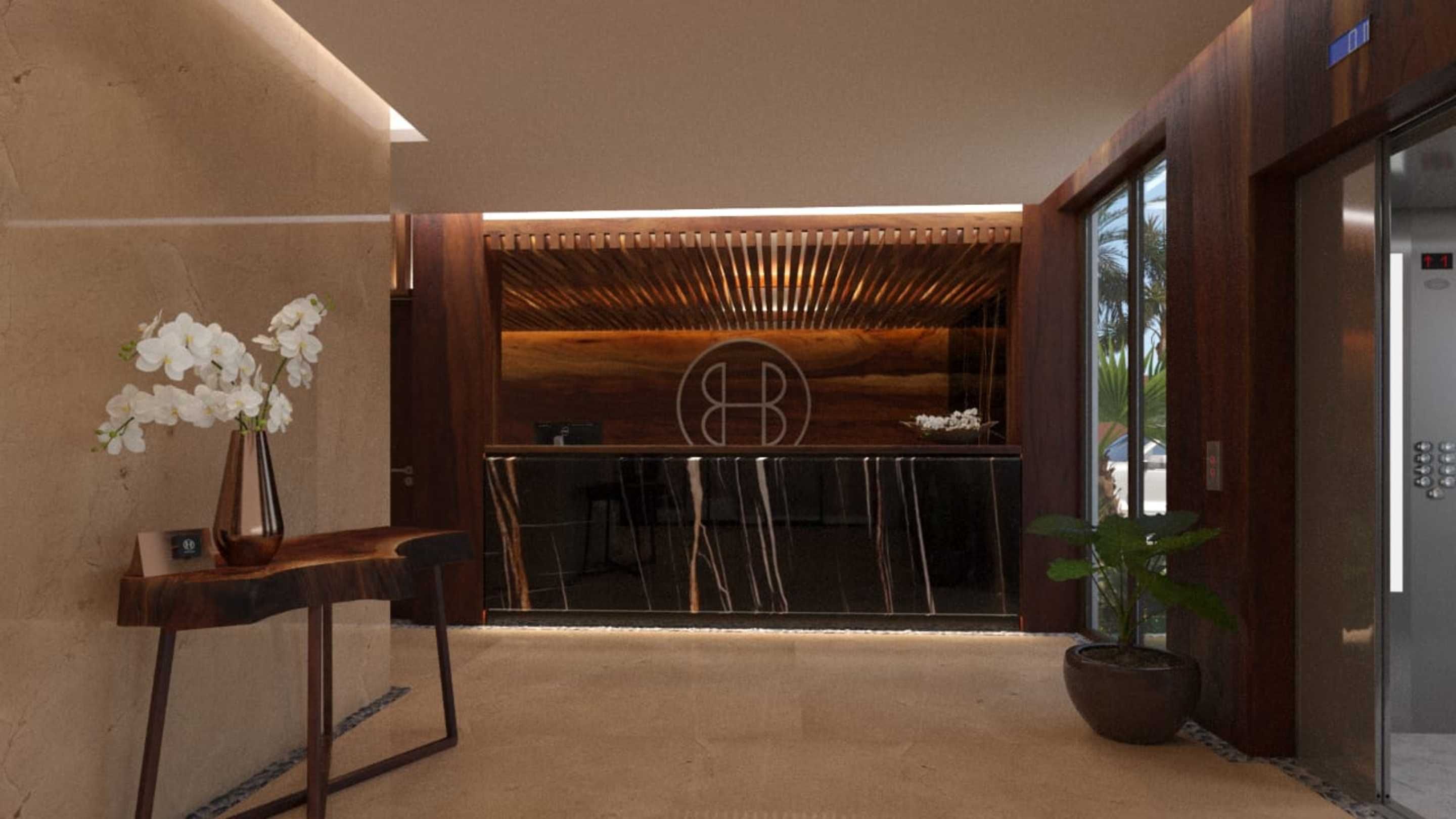 A reception area with a wooden counter, a vase of white flowers, and a potted plant.