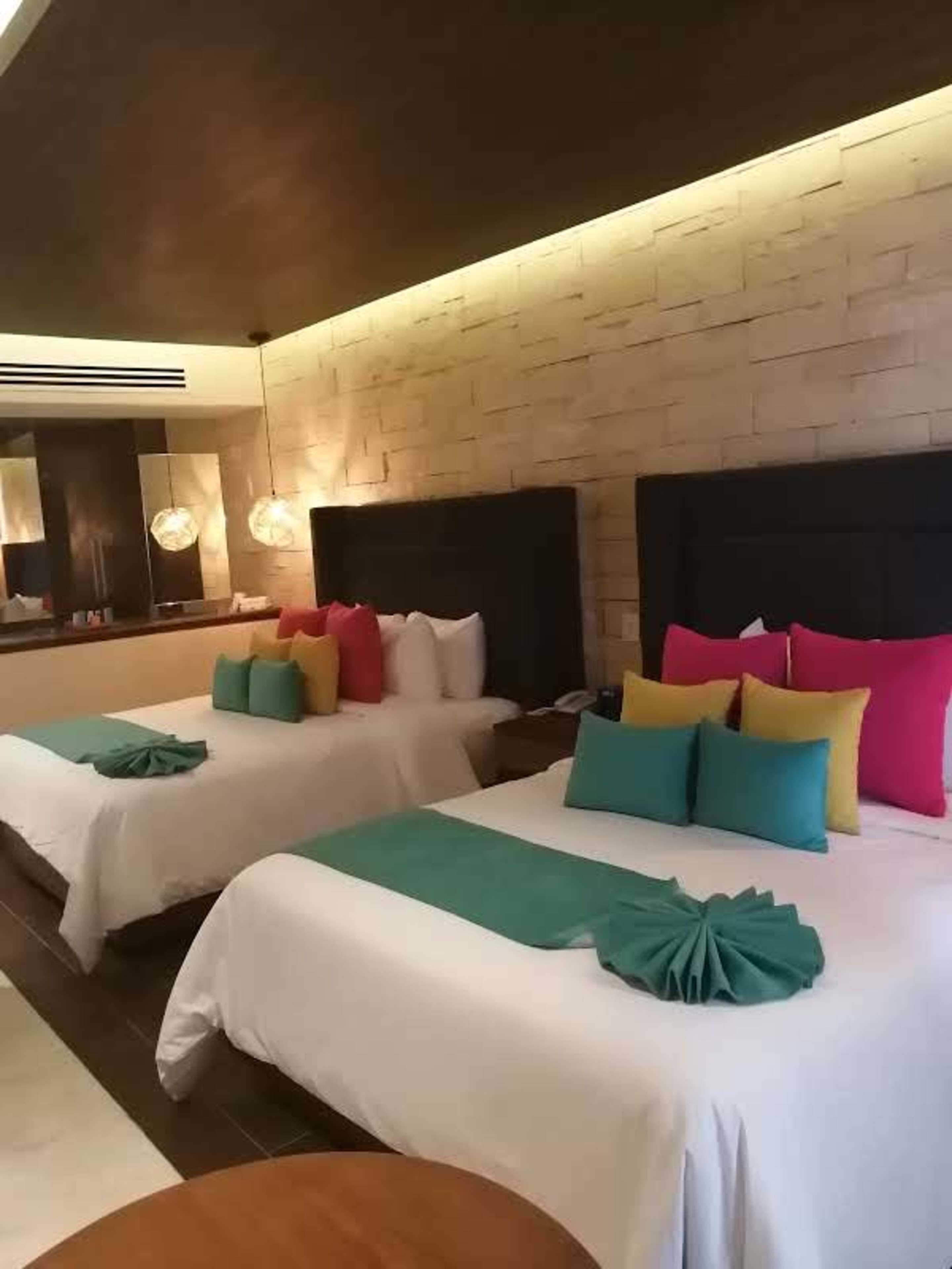 A hotel room with two beds, a large mirror, and a modern design.
