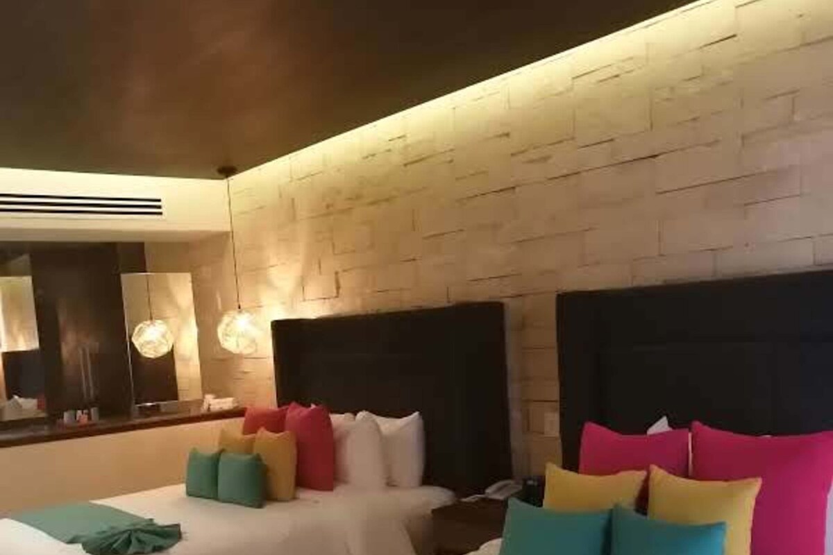 A hotel room with two beds, a large mirror, and a modern design.