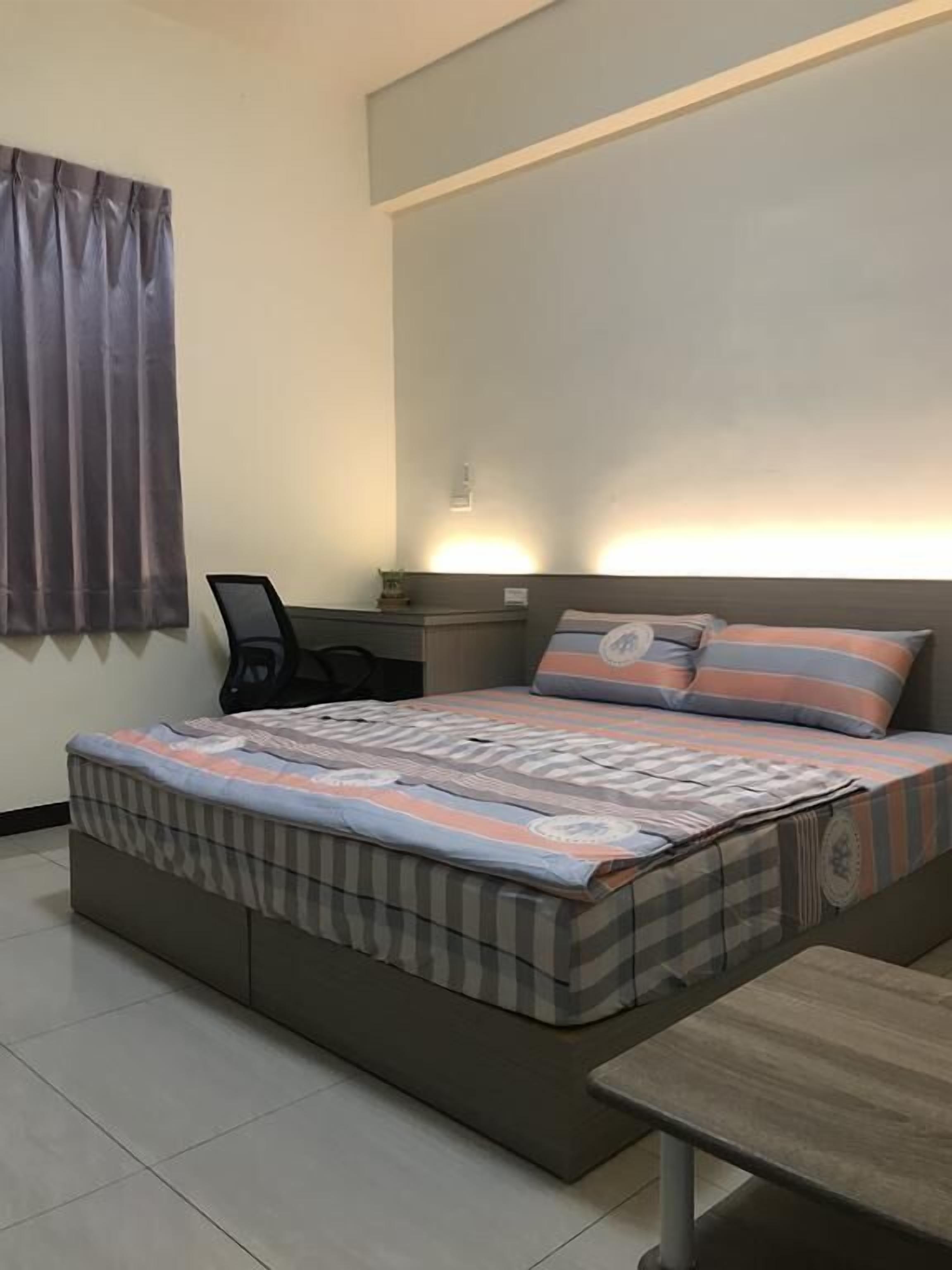Een slaapkamer met een bed, een bureau en een stoel.
