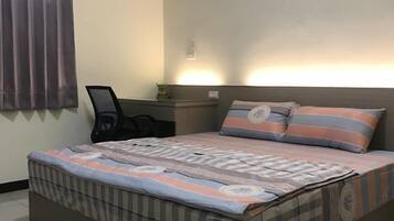 Een slaapkamer met een bed, een bureau en een stoel.