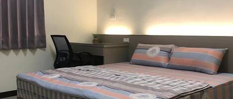 A bedroom with a bed, a desk, and a chair.