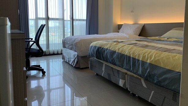 Habitación de hotel con dos camas, un escritorio y una silla.