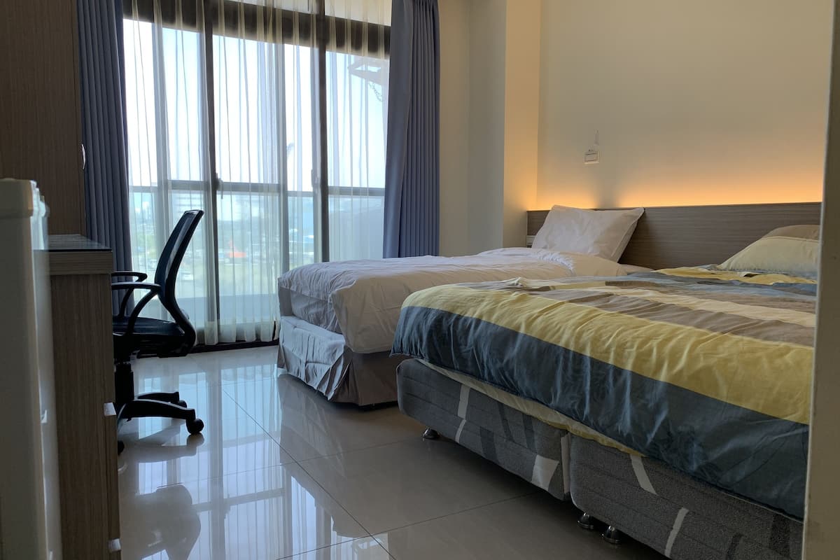 Habitación de hotel con dos camas, un escritorio y una silla.