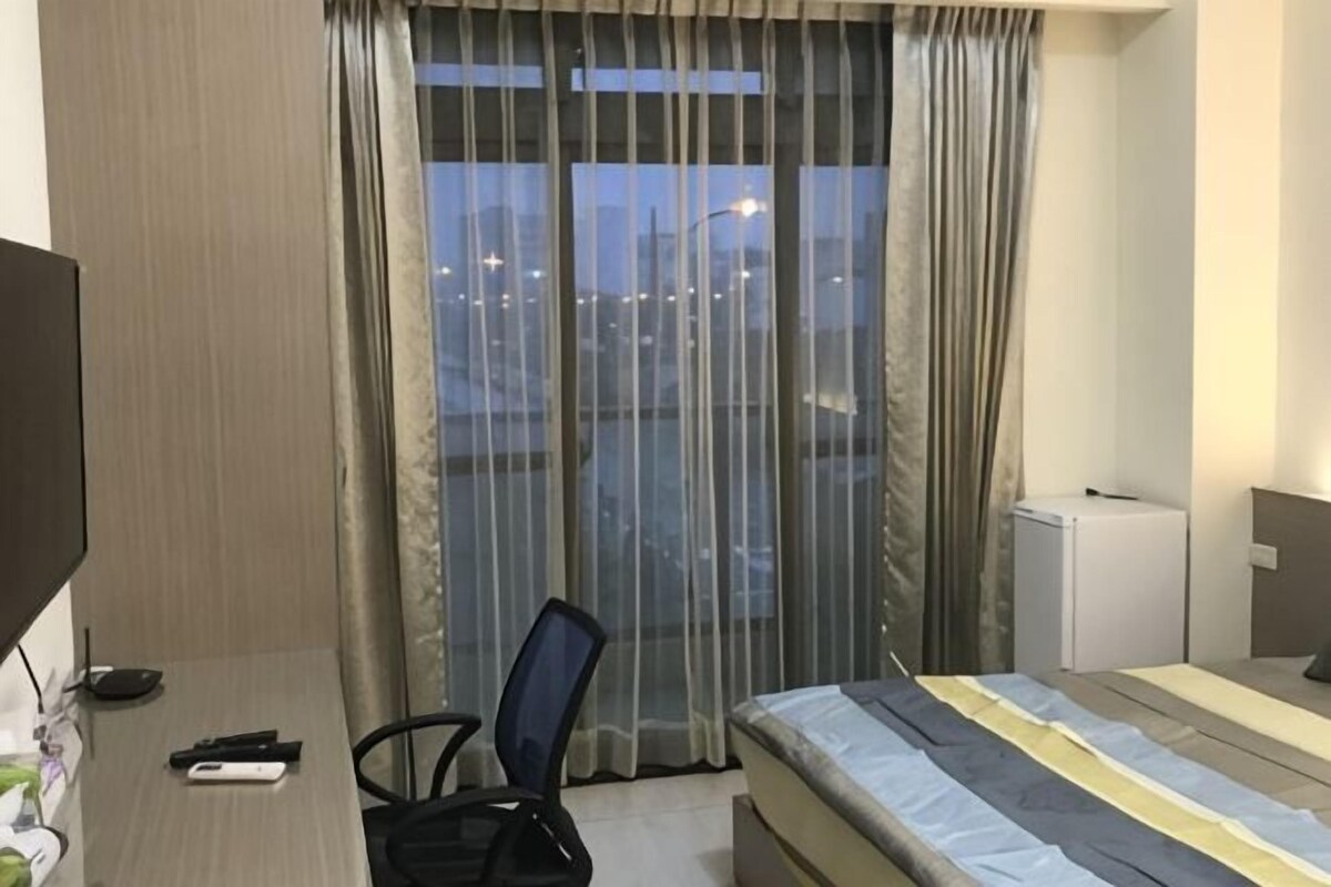 Une chambre d’hôtel avec un lit, un bureau et une chaise, une télévision, un petit réfrigérateur et une vue par la fenêtre.