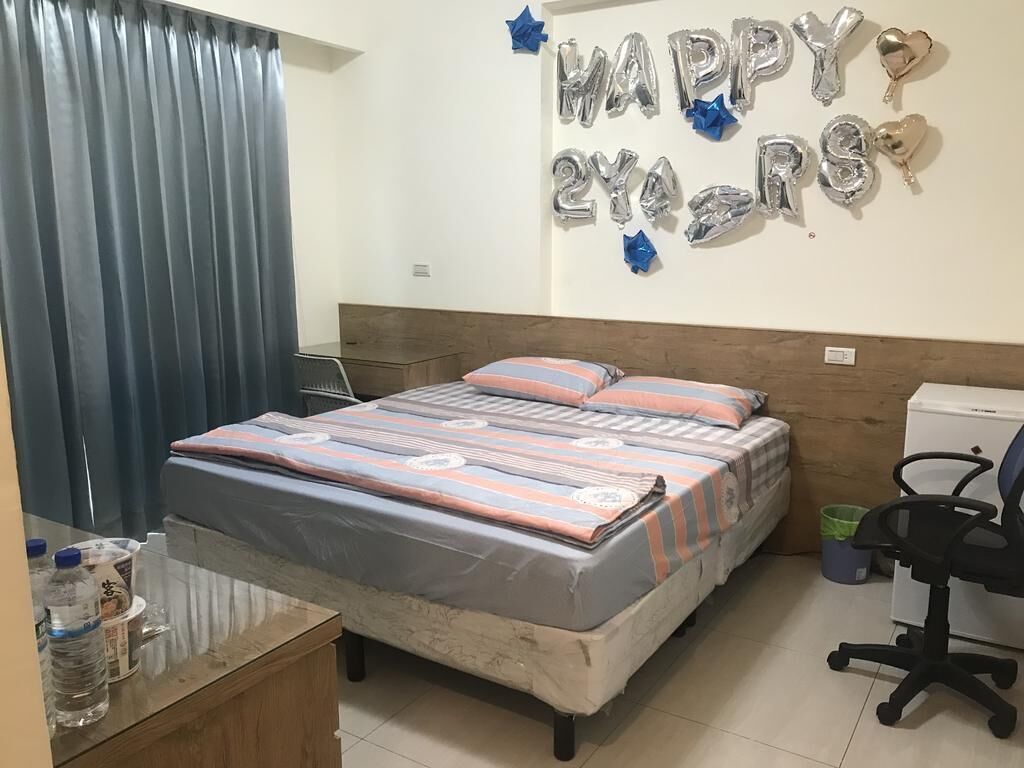 Un dormitorio con una cama, un escritorio y una silla. Hay globos en la pared y una cortina.
