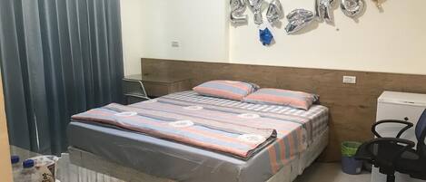 Un dormitorio con una cama, un escritorio y una silla. Hay globos en la pared y una cortina.
