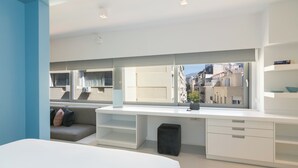 A modern bedroom with a large bed, a desk with a view of the city, and a sofa with cushions. - Athens Color Cube (Athens)