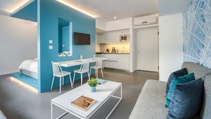 A modern apartment with a blue accent wall, a kitchenette, a dining area, and a living room with a sofa and cushions. - Athens Color Cube (Athens)