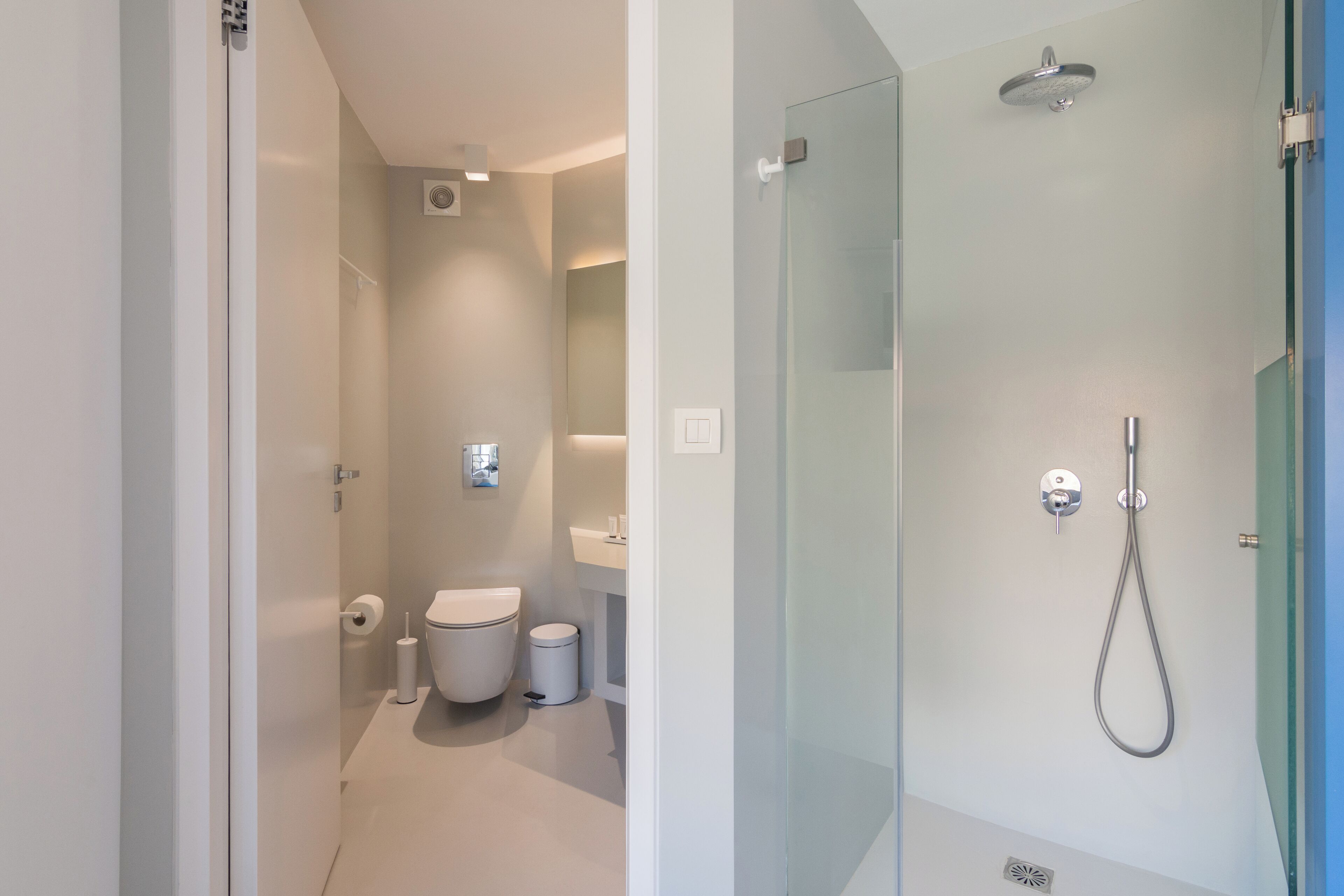 A modern bathroom with a glass shower enclosure, a toilet, and a sink.