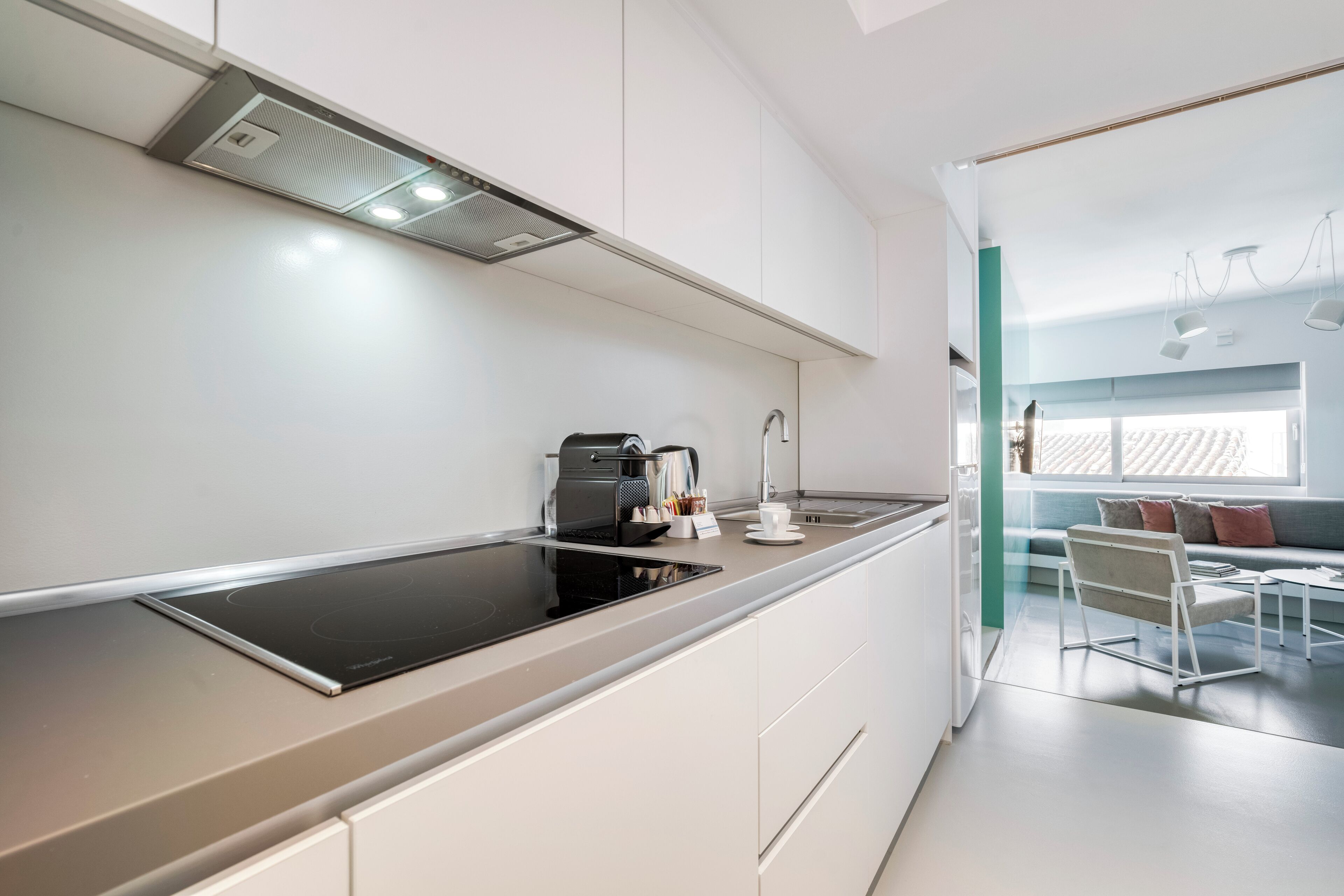 A modern kitchen with a built-in stove, a coffee maker, and a dining area with a table and chairs.