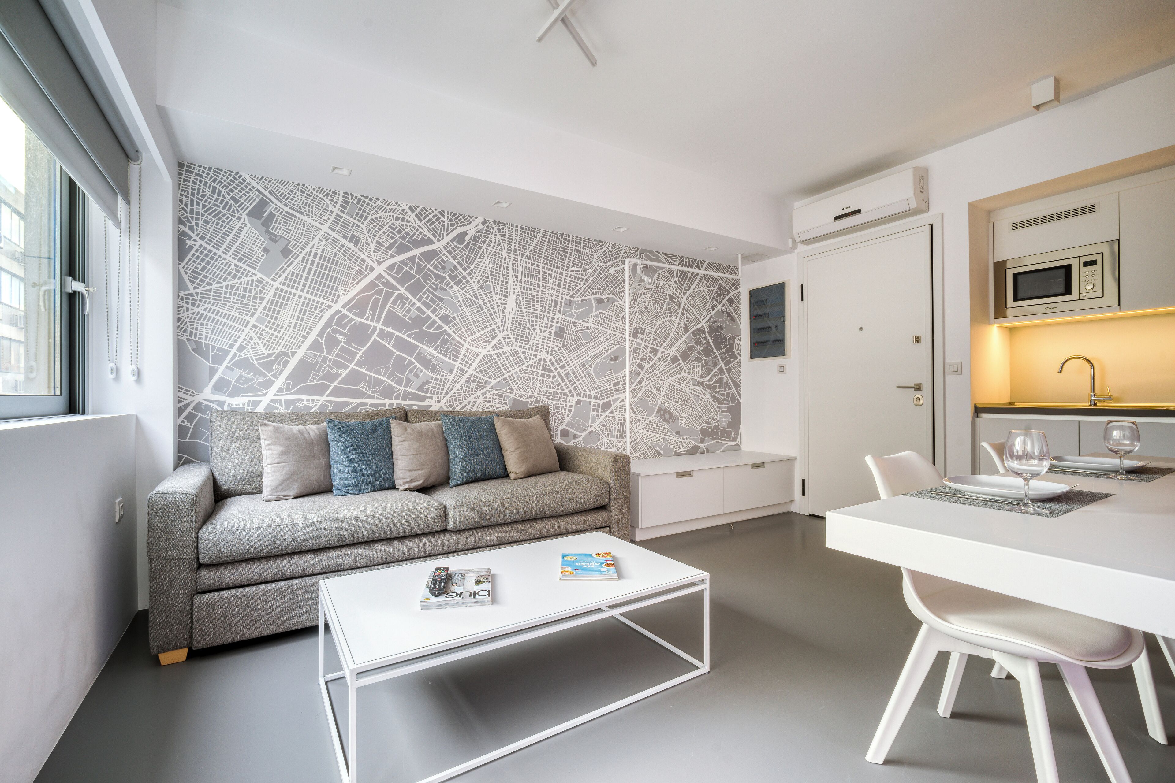 Una sala de estar moderna con sofá, mesa de centro y comedor con mesa y sillas blancas.