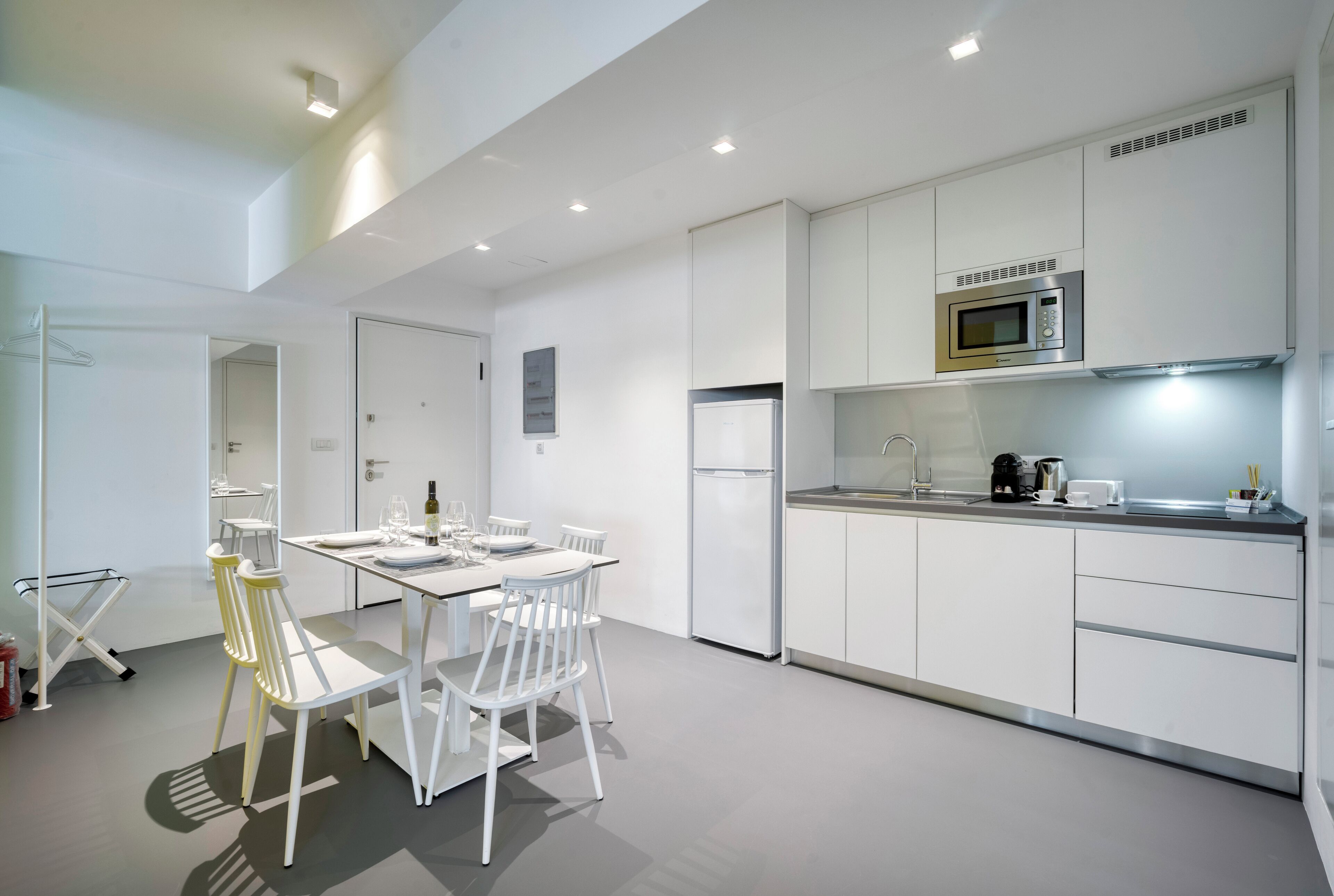 Una cocina moderna con armarios blancos, microondas integrado y un comedor con mesa y sillas.