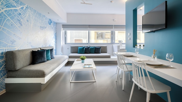 A modern living room with a sofa, coffee table, and dining area with chairs and a TV. - Athens Color Cube (Athens)