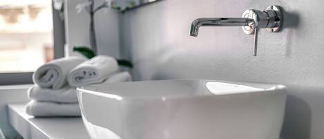 A white ceramic sink with a modern faucet, a mirror above it, and a window in the background.