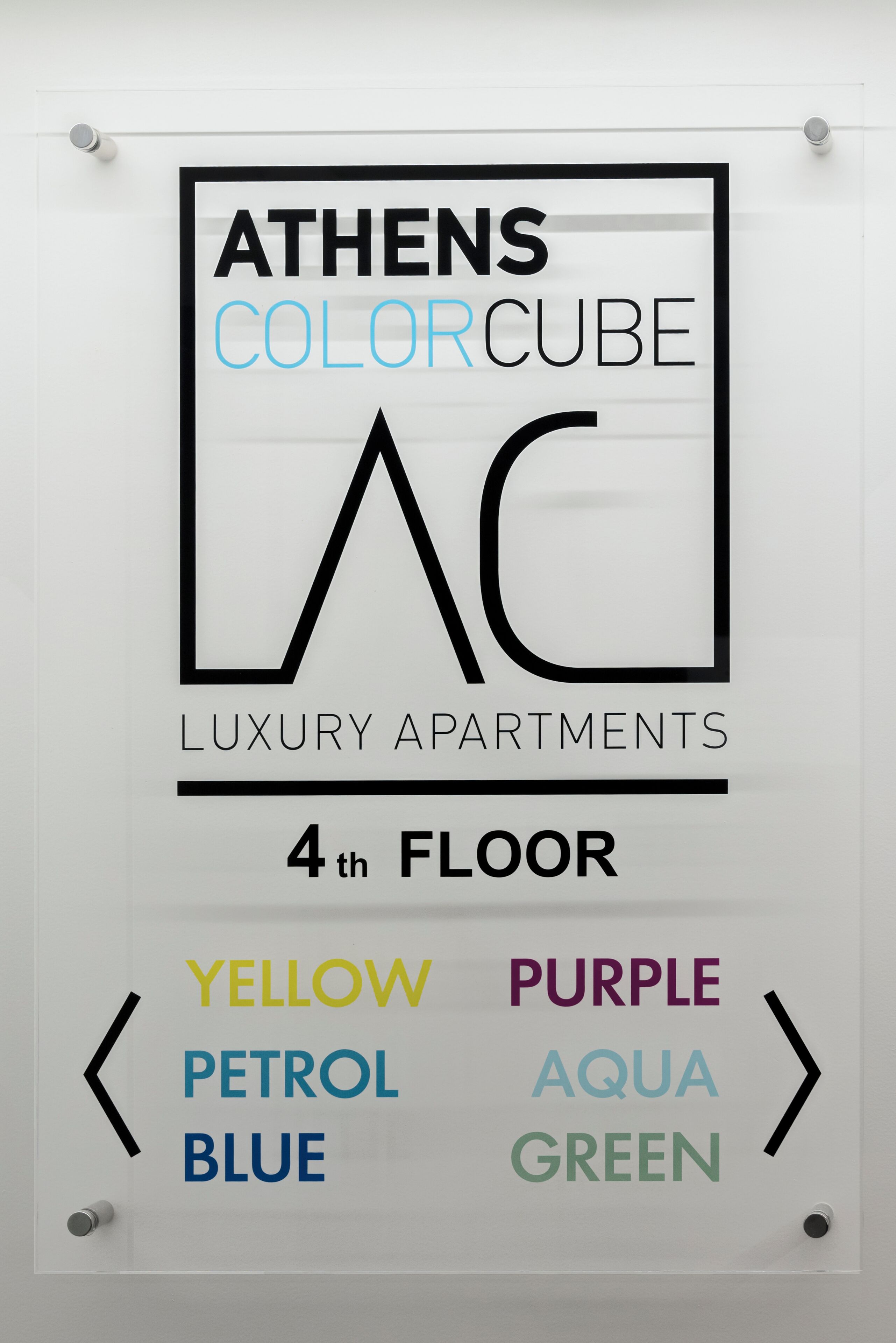 A sign for Athens Colorcube Luxury Apartments on the 4th floor, indicating available colors: Yellow, Purple, Aqua, Blue, and Green.