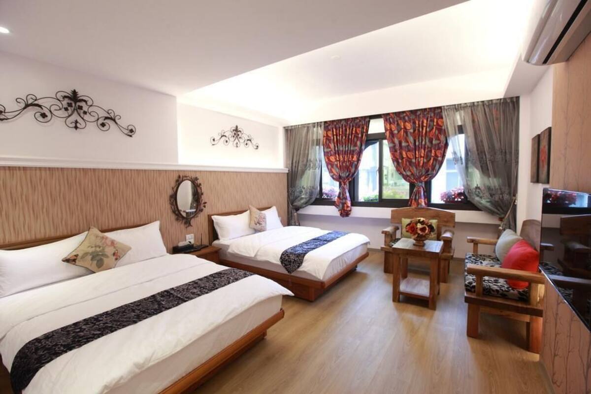 A hotel room with two beds, a wooden desk, a chair, and a TV.
