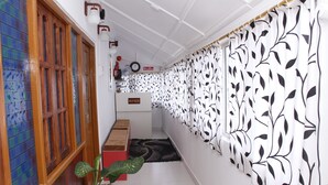A hallway with a help desk, a clock, and a fire extinguisher on the wall. - Ratnoop Inn-enjoy the classic stay (Port Blair)