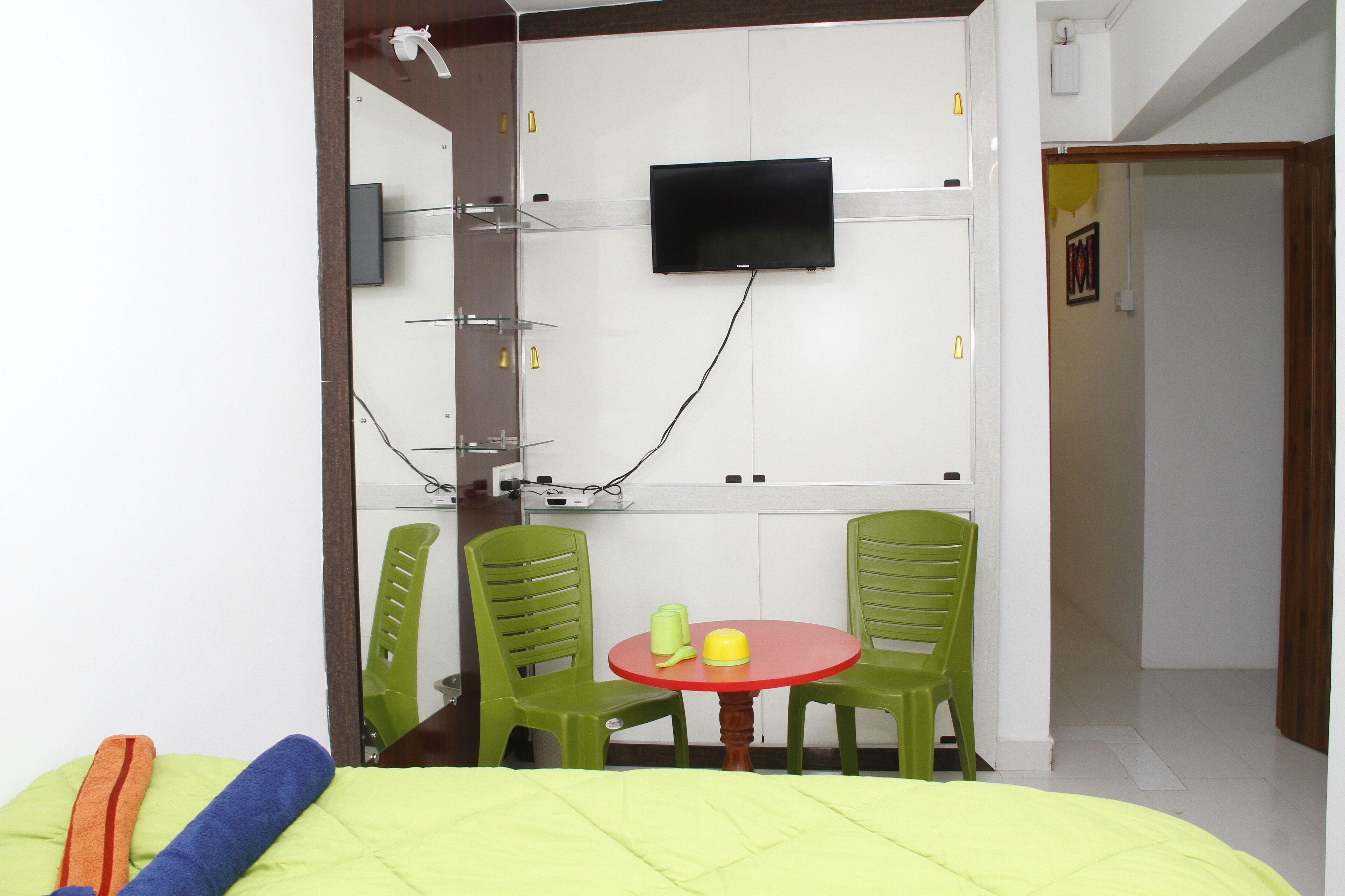 Une petite pièce comprenant un lit, un téléviseur fixé au mur et une table avec deux chaises.