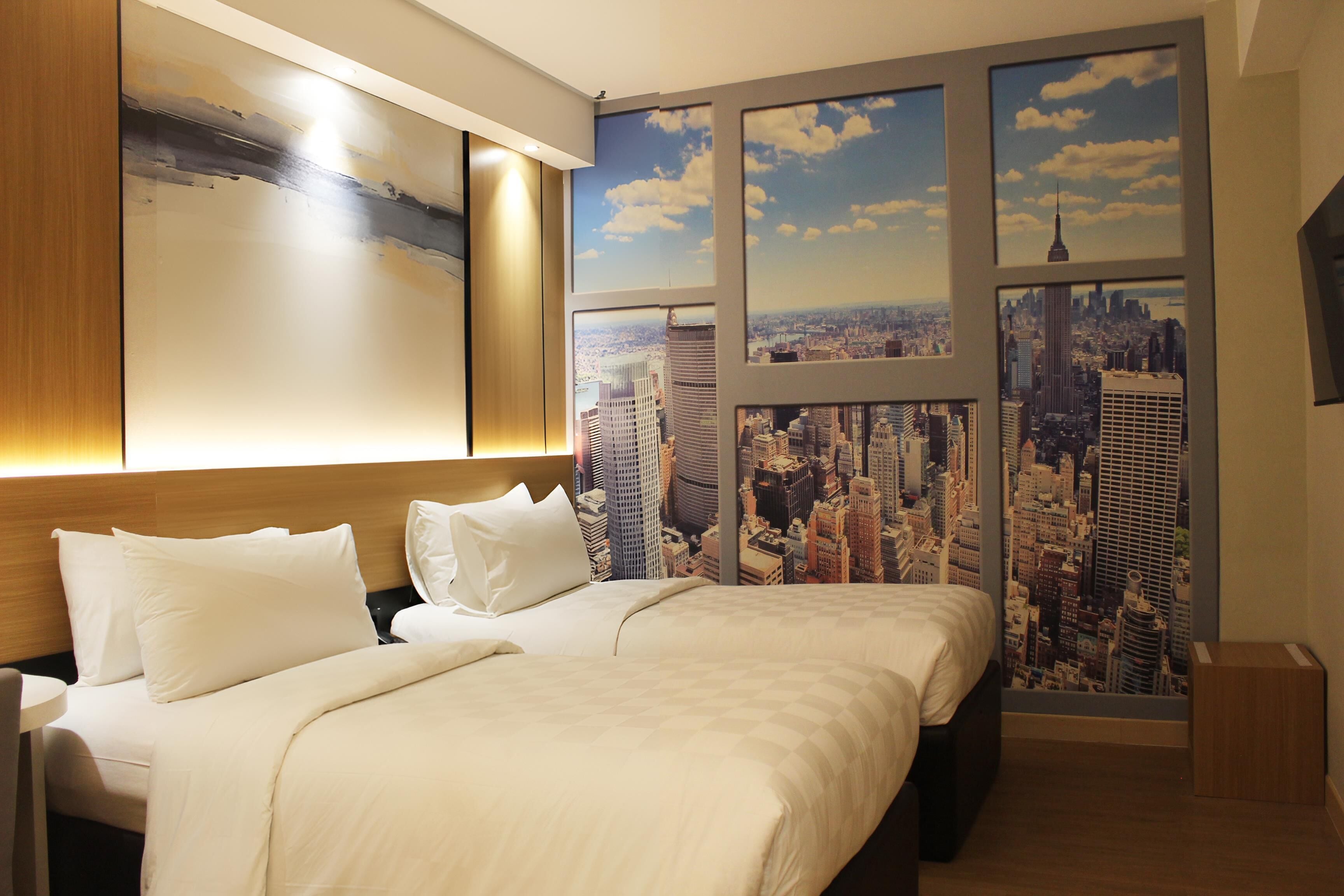 Habitación de hotel con una cama grande, dos almohadas, un cabecero y un mural de un paisaje urbano.