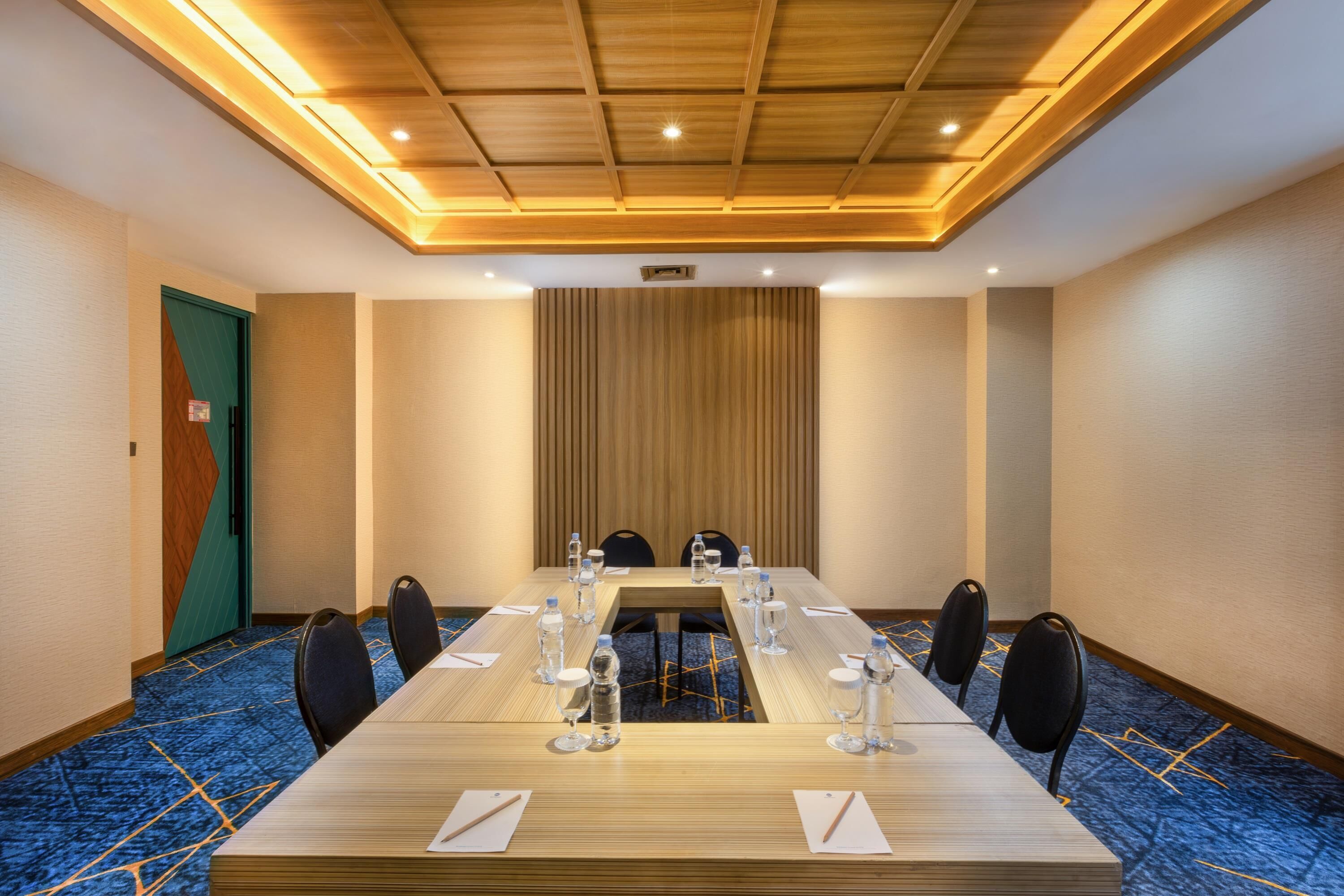 A conference room with a long table, chairs, water bottles, and a carpeted floor.