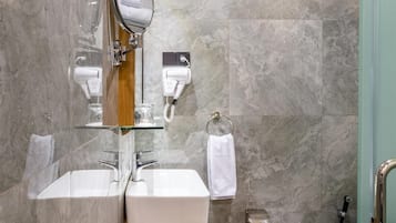 Un baño moderno con dos lavamanos, un inodoro y un tocador con mampara de vidrio.