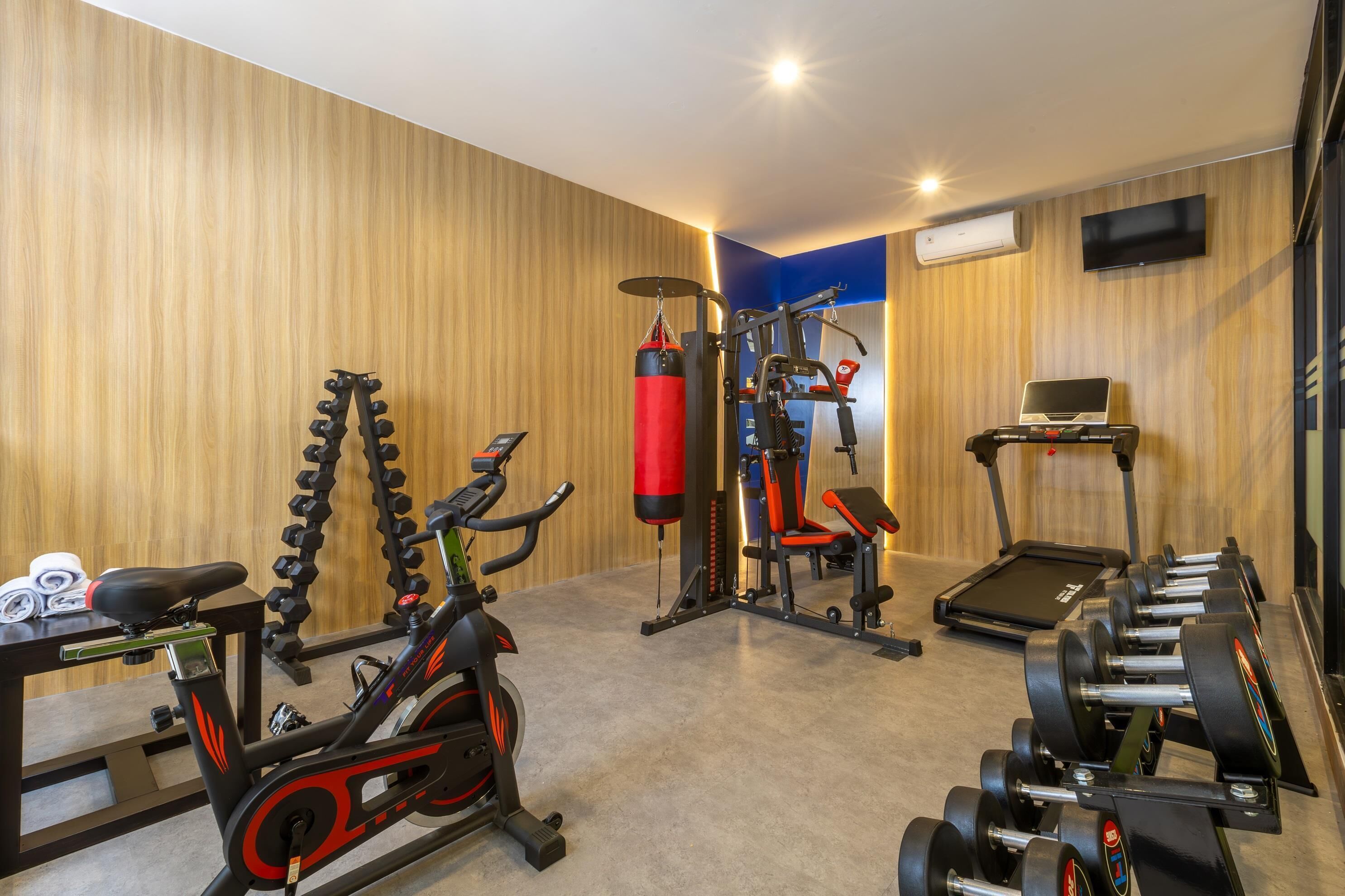 A gym with exercise equipment including a stationary bike, punching bag, and dumbbells.