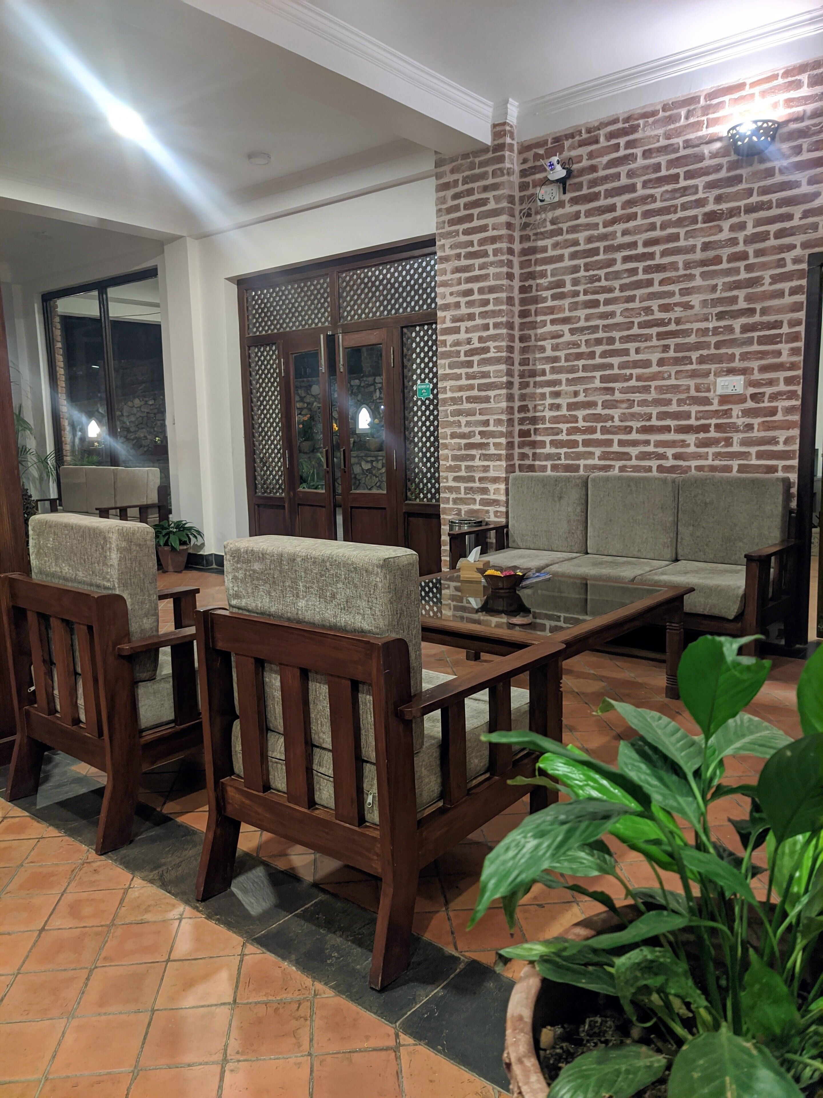 Uma sala de estar aconchegante com parede de tijolos, mobiliário de madeira e piso ladrilhado.