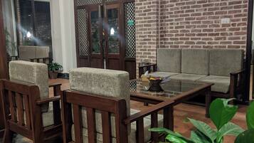 Uma sala de estar aconchegante com parede de tijolos, mobiliário de madeira e piso ladrilhado.