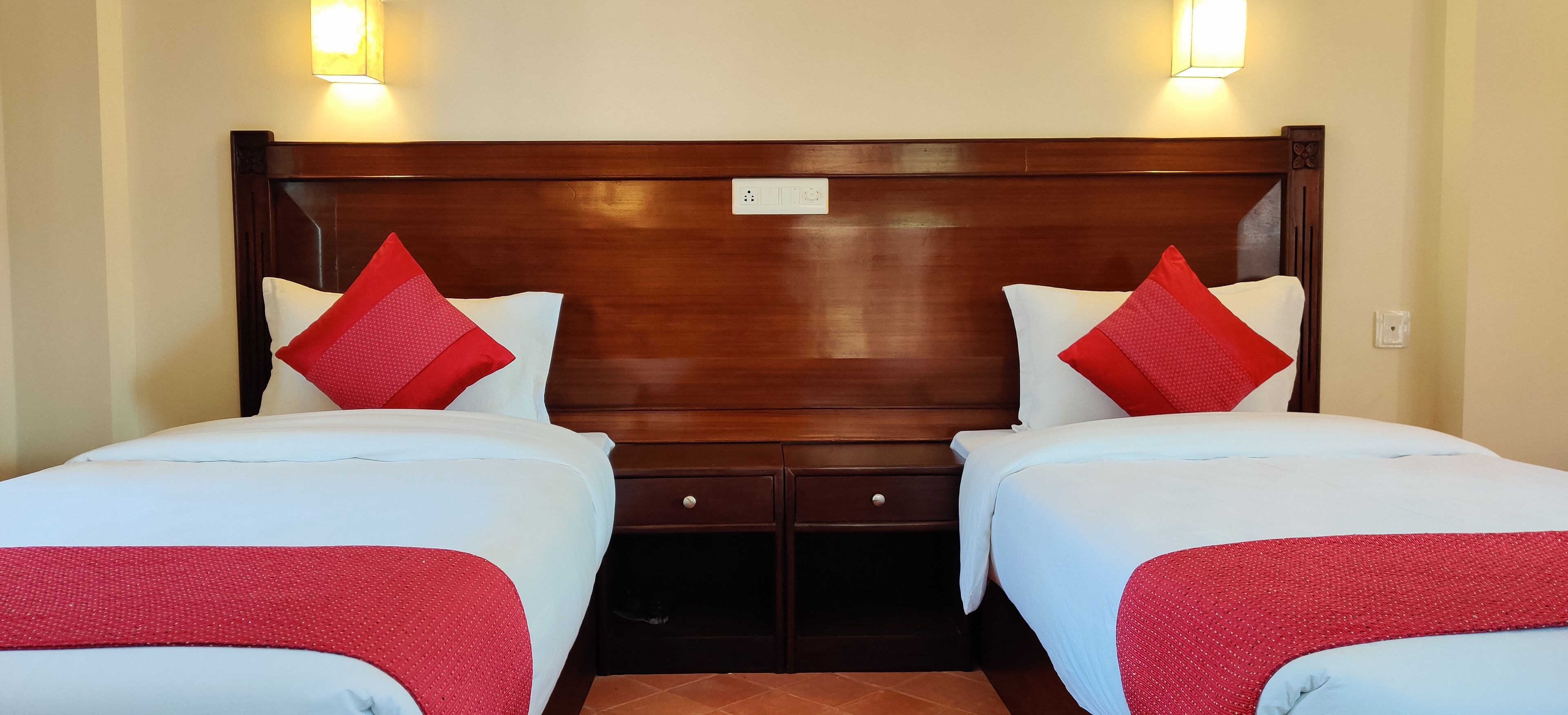 A double bed room with a wooden headboard, two bedside tables, and red and white bedding.