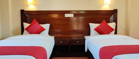 Habitación doble con cama de matrimonio, dos mesitas de noche y ropa de cama roja y blanca.